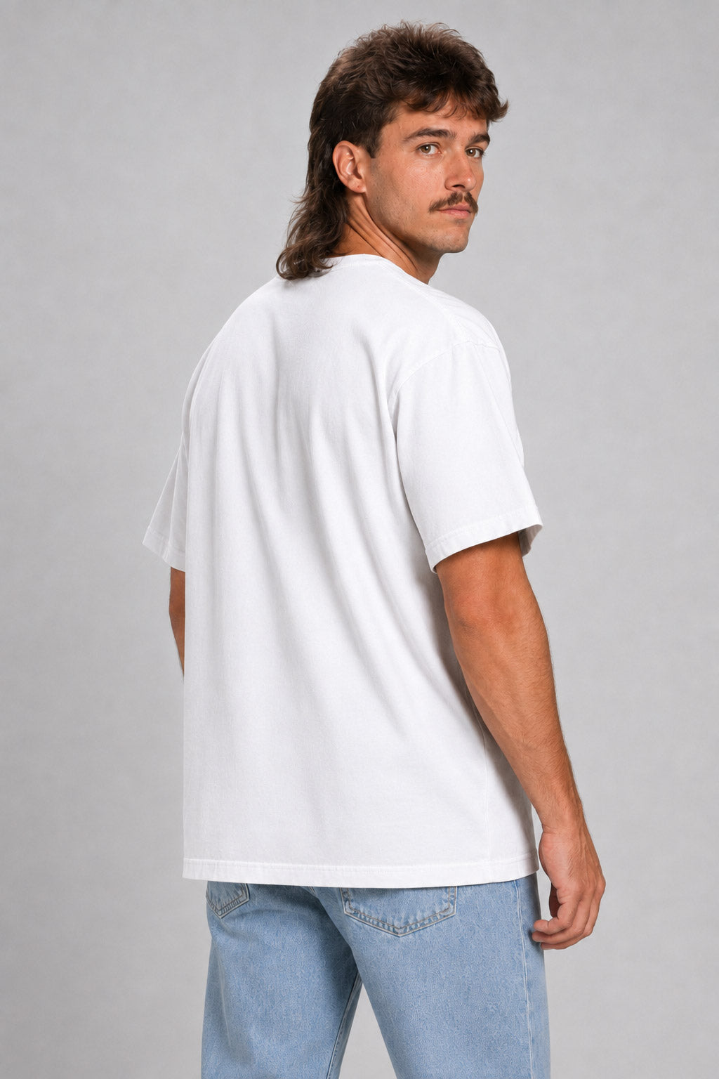 A man with a mullet hairstyle and mustache, shown from the back wearing a plain white short-sleeve t-shirt and light blue jeans, against a solid gray studio background. #white
