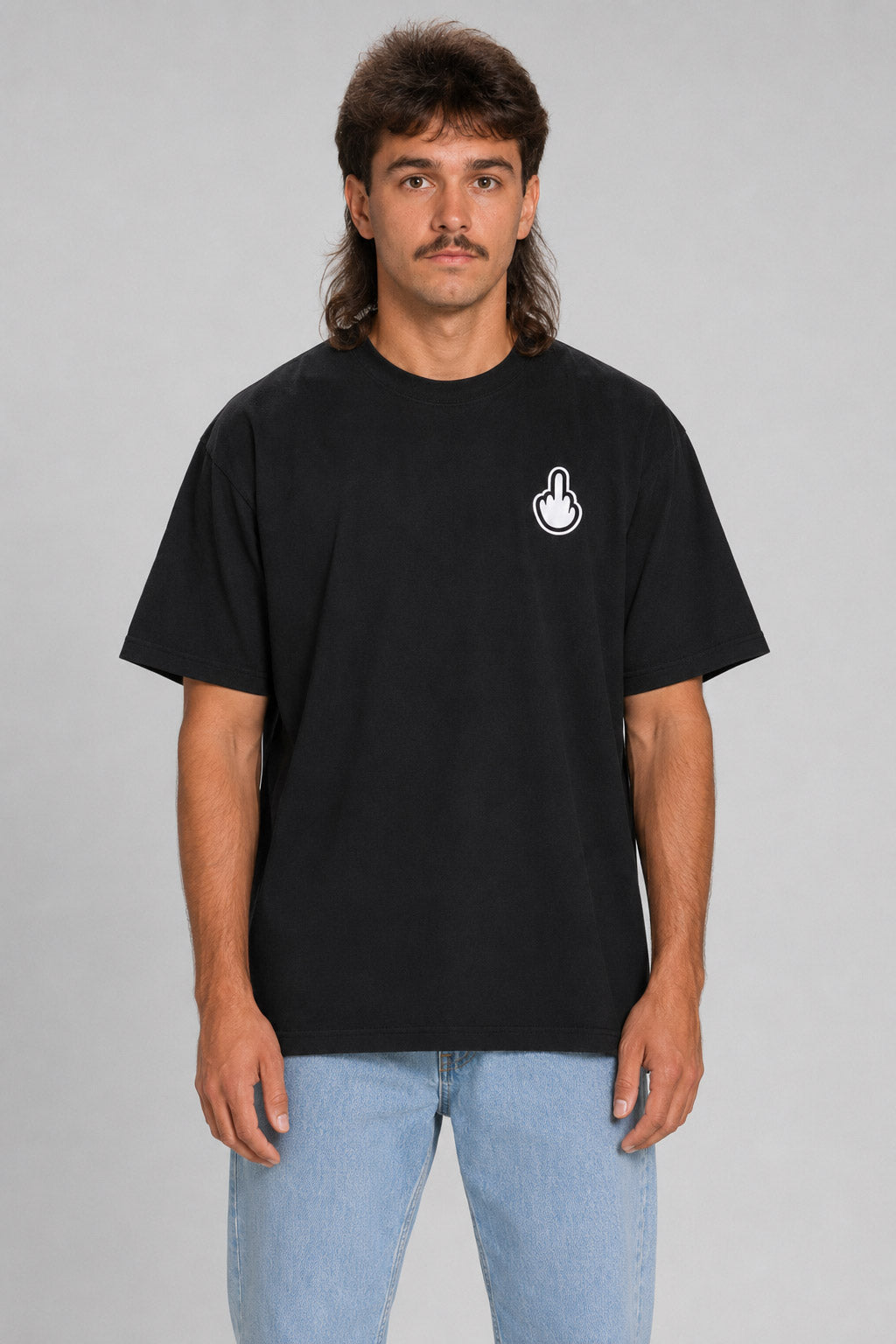 A man wearing a black short-sleeve t-shirt with a small white hand graphic on the left chest, paired with light blue jeans, standing against a solid gray background. #black